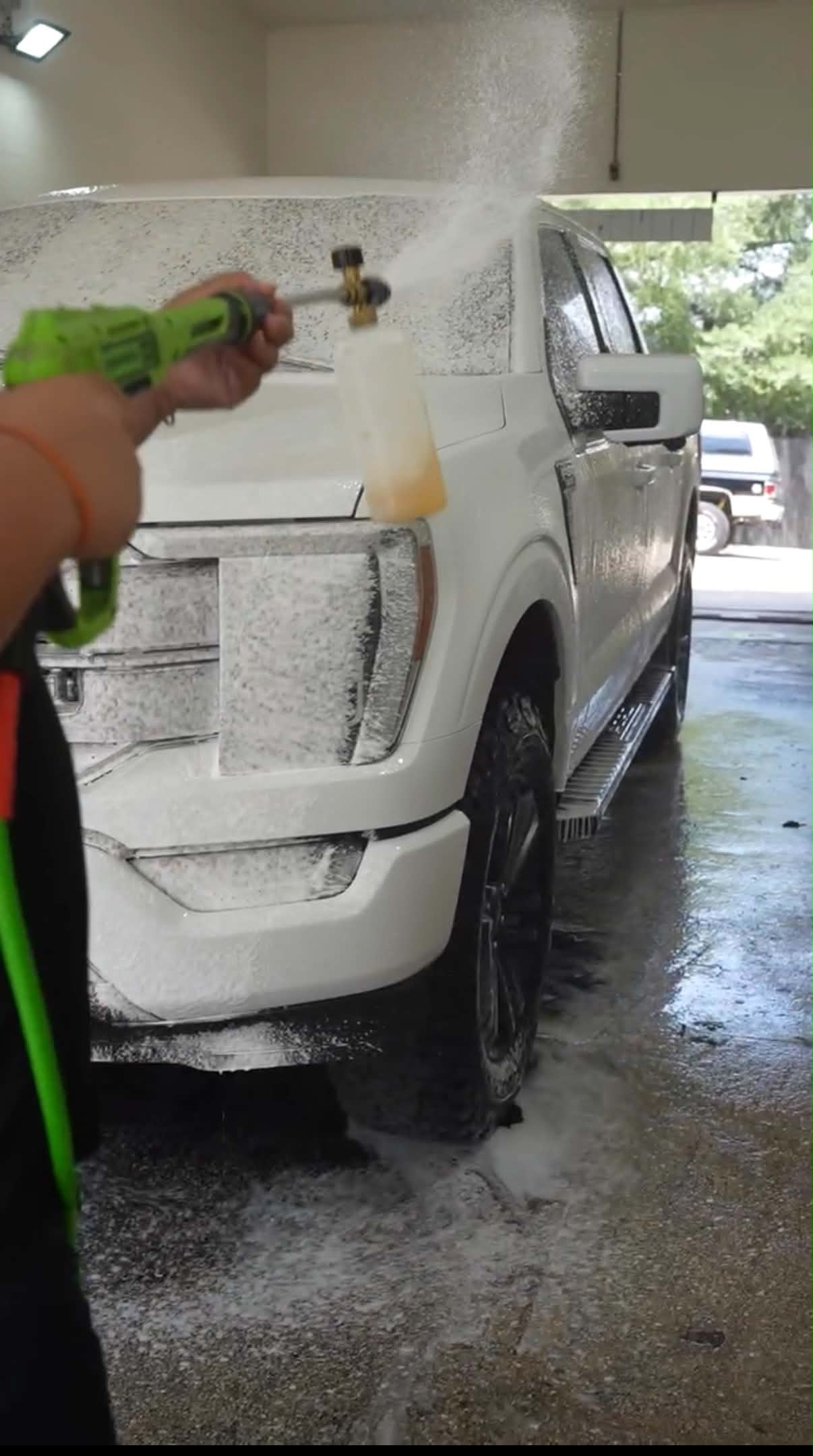 Team member foam washing a white SUV in the wash bay