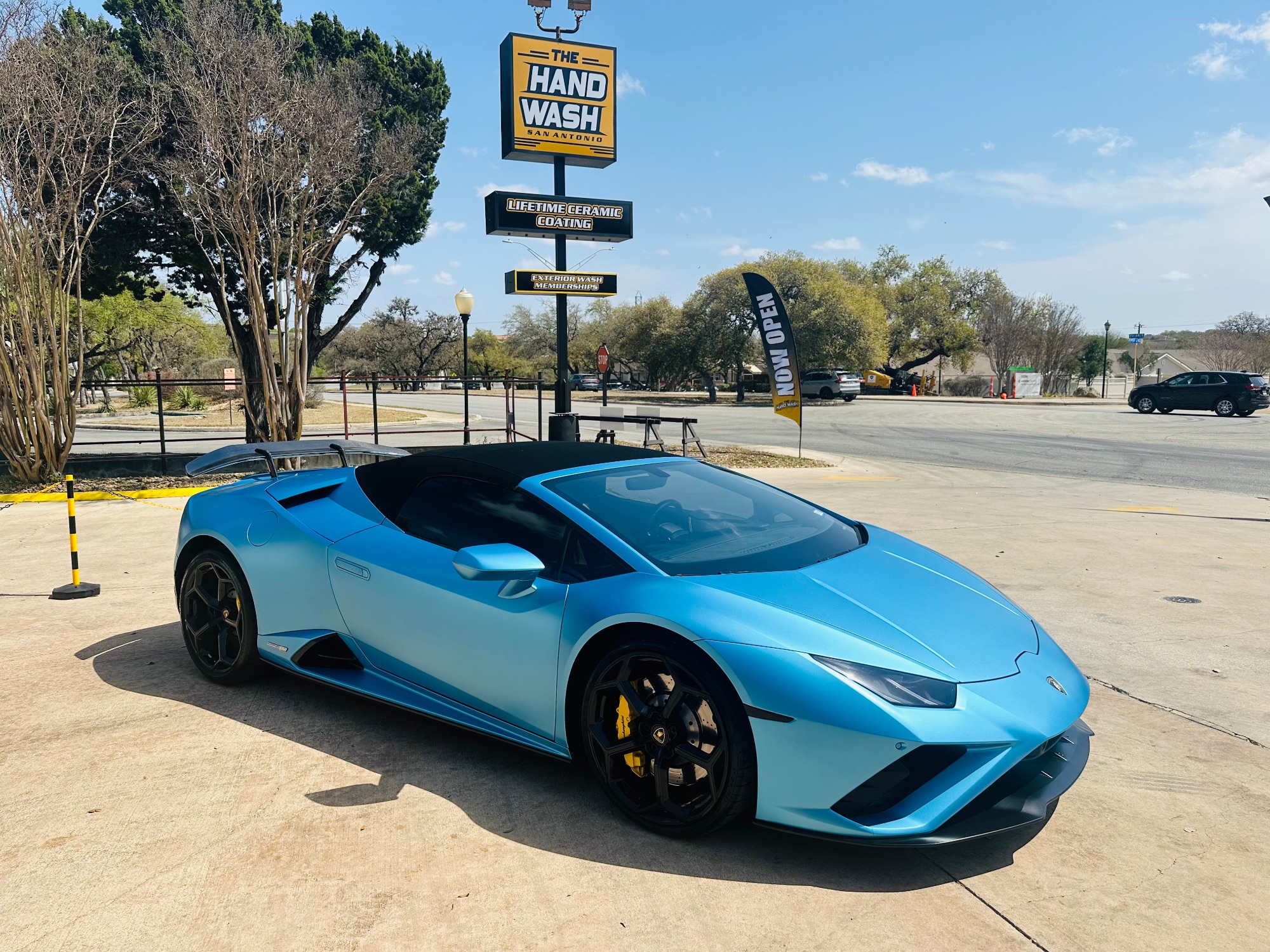 Light blue Lamborghini and The Hand Wash sign viewed from a low angle