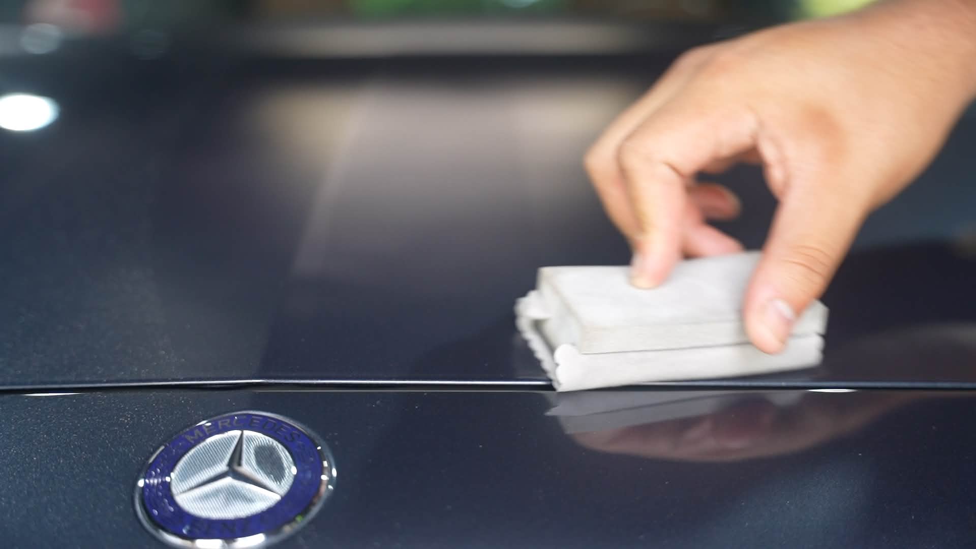Detailer applying ceramic coating to a glossy black Mercedes-Benz hood