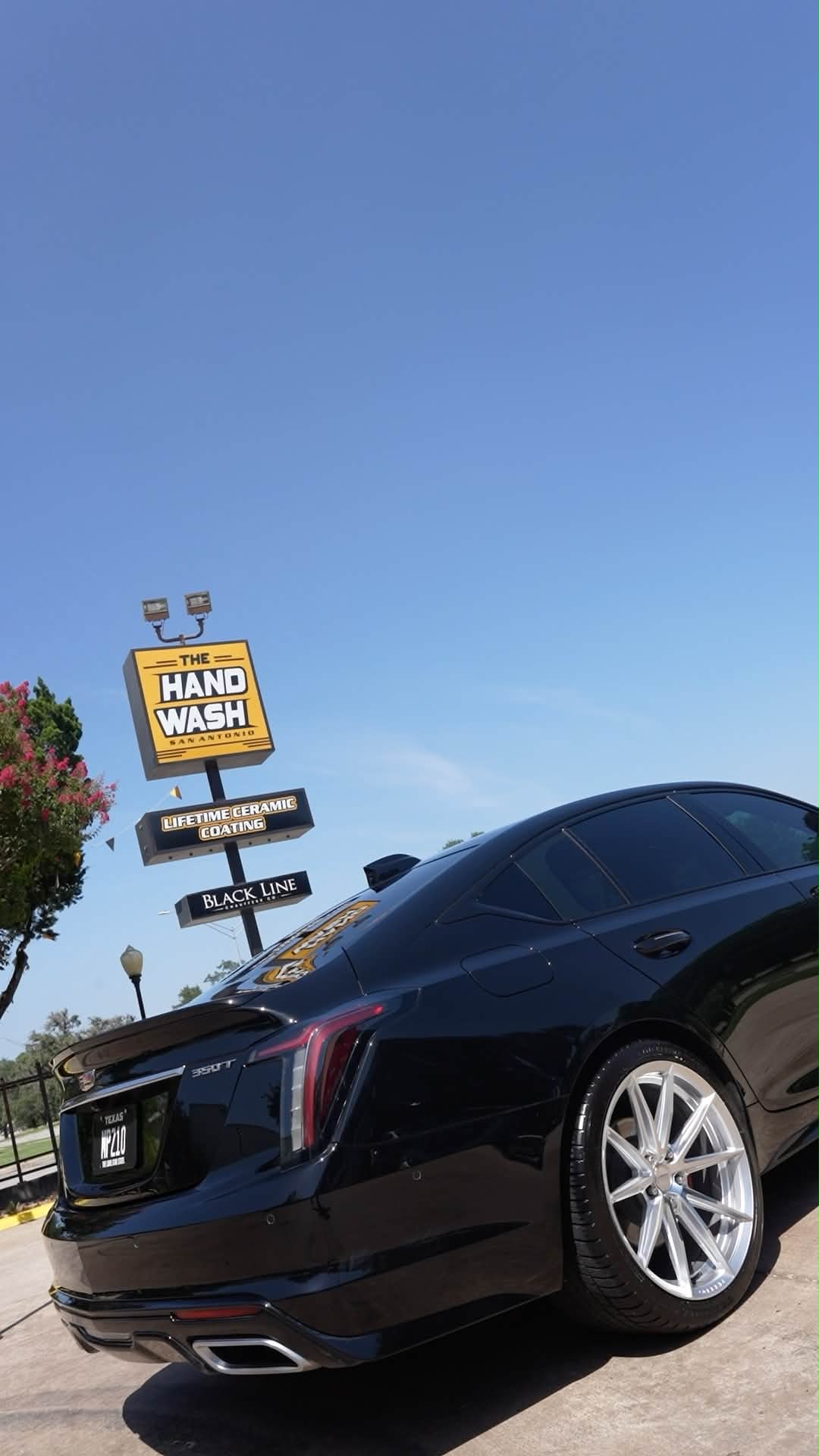 Glossy black Cadillac sedan outside The Hand Wash San Antonio