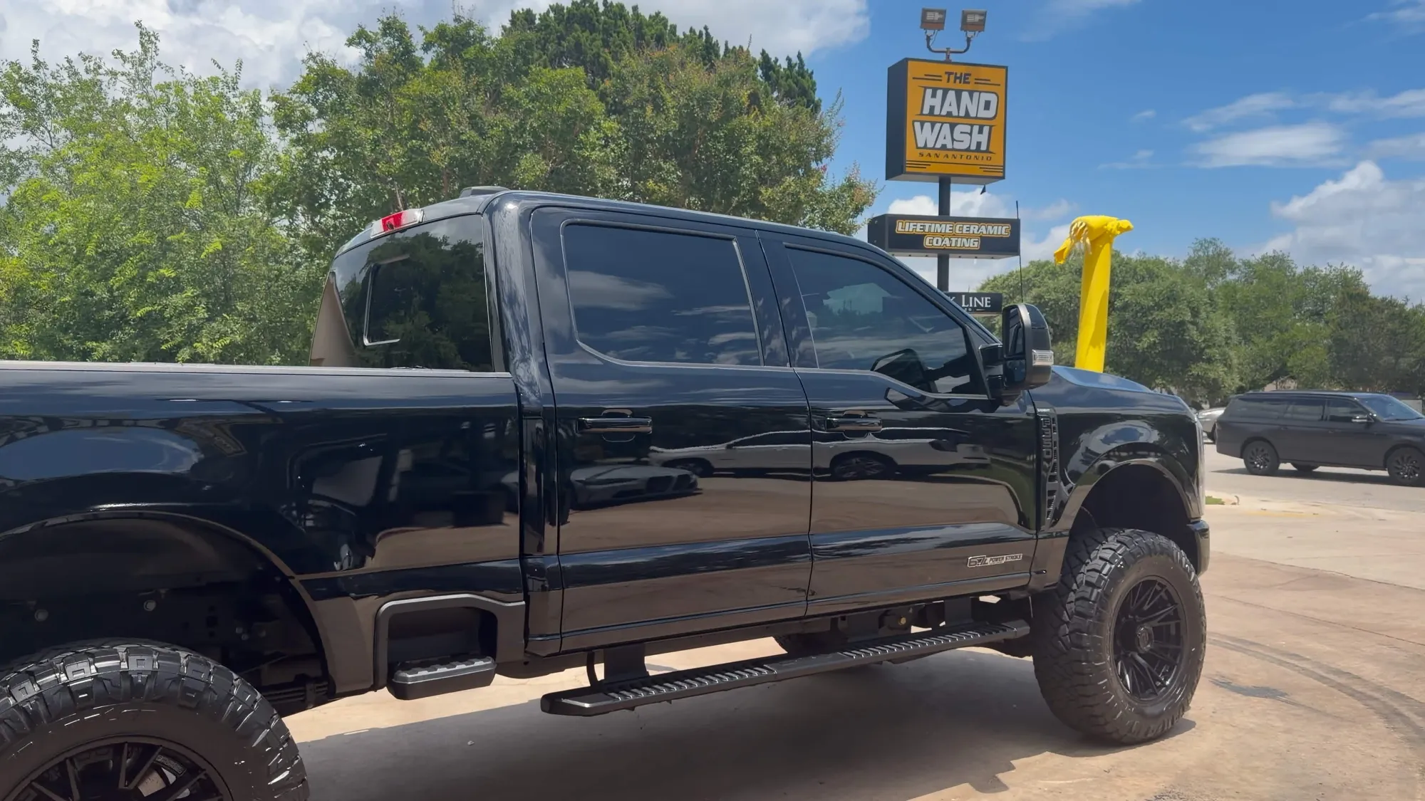 Clean black lifted pickup truck outside The Hand Wash San Antonio