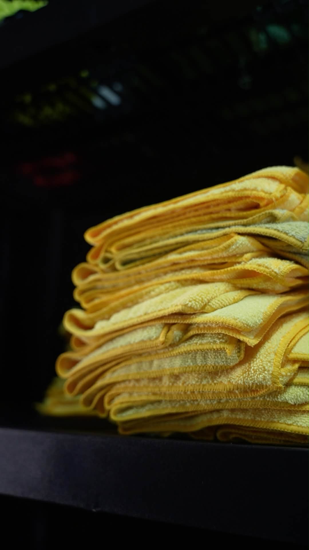 Clean yellow microfiber detailing towels stacked in the shop