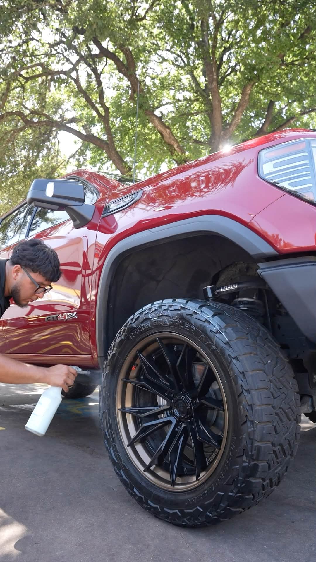 Team member cleaning the wheel of a red pickup truck