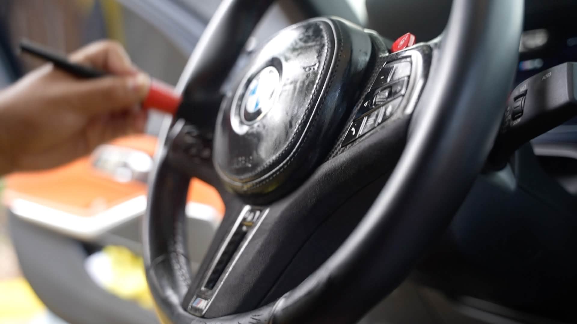 Detailer brushing a black BMW steering wheel